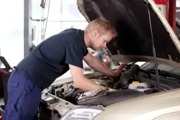 Mężczyzna pracuje przy silniku samochodu, ucząc się na kursie mechanika samochodowego dla dorosłych.