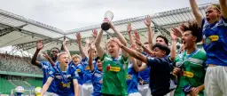 Drużyna piłkarska świętuje zwycięstwo, unosząc puchar na stadionie.