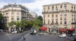 Ulica w 15 dzielnicy Paryża z kamienicami, kawiarnią i apteką. Ruch uliczny, piesi i rowerzysta.