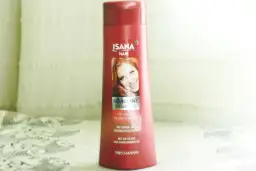 Czerwona butelka szamponu Isana Hair Farbglanz z wizerunkiem rudowłosej kobiety.