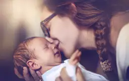 Delikatny pocałunek matki w czoło noworodka. Czy dziecko musi być zameldowane tam gdzie rodzice?