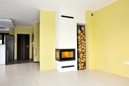 Nowoczesna zabudowa kominka z miejscem na drewno. Instrukcja montażu? Nie, to gotowe rozwiązanie do salonu.