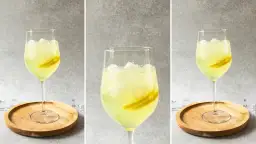 Orzeźwiający drink z limoncello, lodem i plasterkami cytryny, podany na drewnianej podstawce. Idealny na letnie popołudnie.