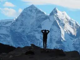 Sylwetka człowieka na tle ośnieżonych gór. Czy to początek choroby wysokościowej, czy tylko chwila zadumy przed dalszą wspinaczką?