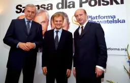 Trzech mężczyzn w garniturach, założyciele Platformy Obywatelskiej, pozuje na tle banera z napisem "Szansa dla Polski".