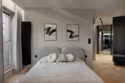 Nowoczesna sypialnia z łóżkiem i dwoma obrazami. Dyskretne gniazdka pokazują, jak rozmieścić kontakty w sypialni, by były estetyczne i funkcjonalne.