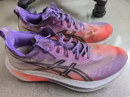 Para biegowych butów Asics Megablast w kolorze fioletowo-pomarańczowym, gotowych na kolejny trening.