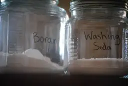 Dwa słoiki z napisem "Borax" i "Washing Soda". Boraks do picia, choć nie jest to zalecane, jest tu przedstawiony jako składnik domowych środków czystości.