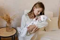 Mama tuli noworodka, myśląc o nowoczesnych imionach dla dziewczyn.