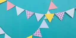 Kolorowa girlanda z trójkątnych chorągiewek w kropki i jednolite, tworzy radosną dekorację.