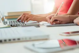 Dwie osoby uczą się, jedna pisze na laptopie, druga notuje. Odkryj skuteczne sposoby na szybką naukę.