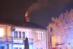 Jasny komin z cegły, z którego lecą iskry, sugeruje, dlaczego lecą iskry z komina. W tle widać dom i drzewo.