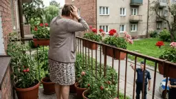 Starsza kobieta na balkonie z kwiatami i pomidorami, policjant wskazuje palcem.