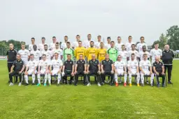 Radomiak Radom zawodnicy pozują do wspólnego zdjęcia. Drużyna w białych strojach, sztab szkoleniowy w czarnych.