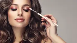 Kobieta z makijażem oczu w odcieniach różu i brązu, aplikowany pędzelkiem.