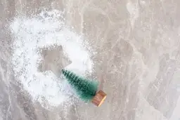 Mała choinka w sztucznym śniegu na marmurowym tle.