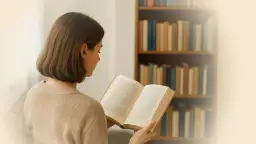 Junge Frau liest ein Buch vor einem Bücherregal.