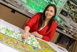 Kobieta w czerwonej marynarce pracuje nad modelem urbanistycznym, pokazując, co można robić po gospodarce przestrzennej: projektować i tworzyć przyszłość miast.