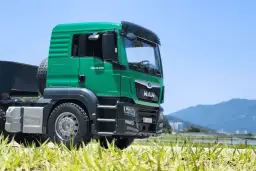 Zielona ciężarówka MAN TGS 26.500 na tle nieba i gór. Zastanawiasz się, ile zarabiają kierowcy tirów?