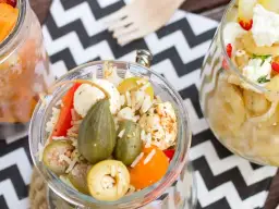 Słoiki z sałatkami: ryż, warzywa, ser mozzarella i oliwki.