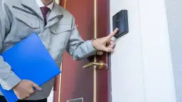 Mężczyzna w szarym stroju z teczką naciska domofon. Czy pracodawca może sprawdzić pracownika na L4?