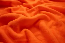 Pomarańczowy polar, miękki i ciepły, idealny na chłodne dni. Z czego jest polar? Z poliestru, który zapewnia komfort i trwałość.