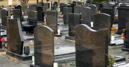 Nagrobki na cmentarzu, z kwiatami i ławką.