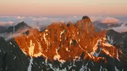 Zachód słońca maluje na pomarańczowo skaliste zbocza, a śnieg lśni na tle chmur. Widok na mięguszowiecki szczyt czarny zapiera dech.