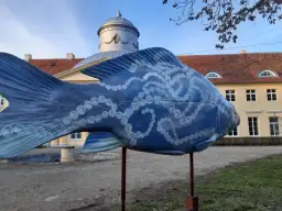 Niebieska rzeźba ryby z perłami zdobi teren w Dolinie Baryczy, idealne miejsce na trasy spacerowe.