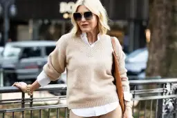 Elegancka kobieta po 50-tce w beżowym swetrze i białej koszuli. Stylowa moda dla 50 latki.