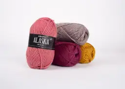 Kłębek różowej włóczki Drops Alaska z etykietą, obok inne kłębki w kolorach szarym, bordowym i musztardowym. Idealne na czapkę i szalik.