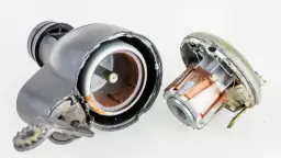 Rozłożone dynamo rowerowe z widocznymi uzwojeniami i wałkiem, pokazujące, jak działa dynamo.