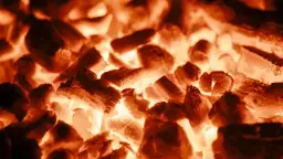 Żarzące się brykiety węgla drzewnego, rozpalone bez użycia rozpałki. Intensywna czerwień i pomarańcz przeplatają się, tworząc obraz żaru.