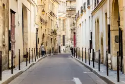 Urokliwa uliczka w paryskiej dzielnicy Le Marais, z kamiennymi budynkami i latarniami.
