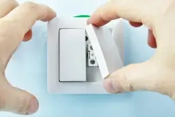 Montaż włącznika schodowego, klucz do tego, jak podłączyć lampę na 2 włączniki. Dłonie montują białą ramkę.