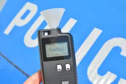 Alkomat z ustnikiem gotowy do pomiaru. Ekran pokazuje "Dmuchaj", wyjaśniając jak działa alkomat.