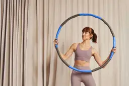 Kobieta z hula hop zastanawia się, czy hula hop odchudza. Ćwiczenia z hula hop mogą pomóc w redukcji tkanki tłuszczowej.