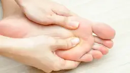 Dłonie masujące podeszwę stopy, widoczne palce i pięta.