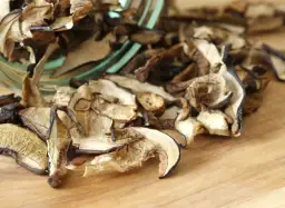 Suszone grzyby na desce. Zastanawiasz się, jak długo gotować suszone grzyby, by były idealne? Oto one, gotowe do namoczenia.