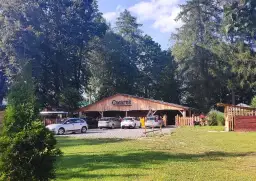 Drewniana restauracja Gwarek w Polańczyku, otoczona zielenią, z zaparkowanymi samochodami.