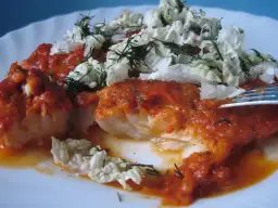 Pyszny dorsz w sosie pomidorowym, udekorowany świeżym koperkiem i chrupiącą kapustą. Idealny obiad!