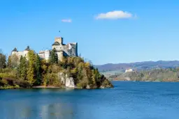 Zamek na skale nad jeziorem, jesienne kolory drzew, piękne jeziora polskie.