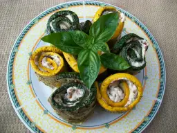 Roladki z cukinii i żółtej dyni faszerowane kremowym farszem, ozdobione gałązką bazylii. Idealne jako przystawka, do czego jeszcze?