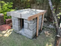 Budowa pieca chlebowego w ogrodzie. Konstrukcja z bloczków betonowych z drewnianym szalunkiem pod strop.
