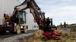 Koparka z zamontowaną głowicą obrotową do koparki, gotowa do pracy przy budowie drogi.