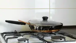Stara, zniszczona patelnia na kuchence gazowej. Zastanawiasz się, gdzie wyrzucić starą patelnię?