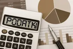 Kalkulator z napisem "PODATKI" na tle wykresów i tabel. Obraz sugeruje analizę, od jakiej kwoty płaci się podatek od sprzedaży.