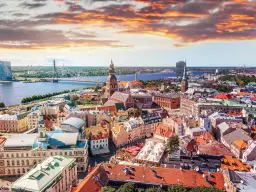 Widok na Rygę z lotu ptaka, z rzeką i mostem w tle. Widać urokliwe kamienice i place, idealne miejsca, by zastanowić się, co zjesc w Rydze.