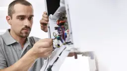 Fachowiec dokonuje przeglądu instalacji w urządzeniu, zapewniając sprawny **serwis Saunier Duval**.