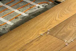 Drewnopodobne płytki układane na ogrzewaniu podłogowym z widocznymi krzyżykami dystansowymi.